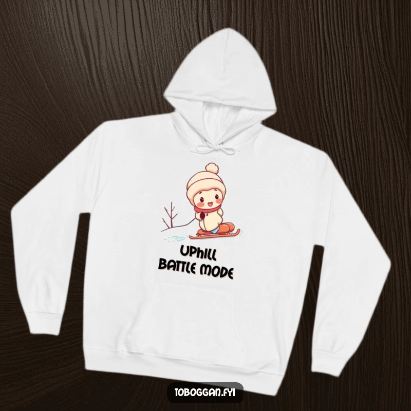 Funny hoodie displays a character with flushed cheeks, straining to shove a sled up a snowy hill, a humorous depiction of perseverance and hard work.