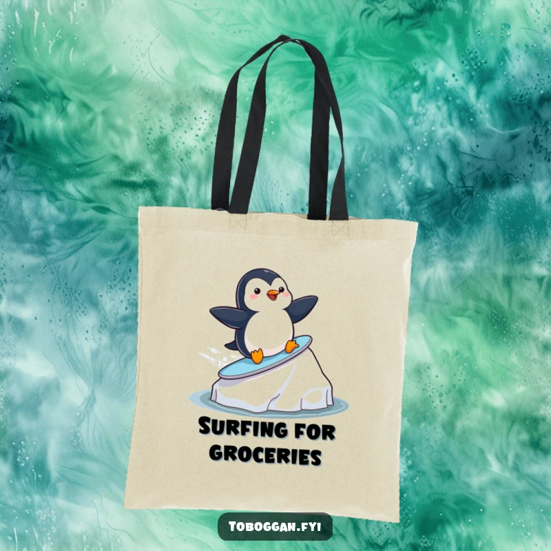 Funny playful penguin surfing on an iceberg on a durable tote bag, a cute and humorous accessory for beach lovers.